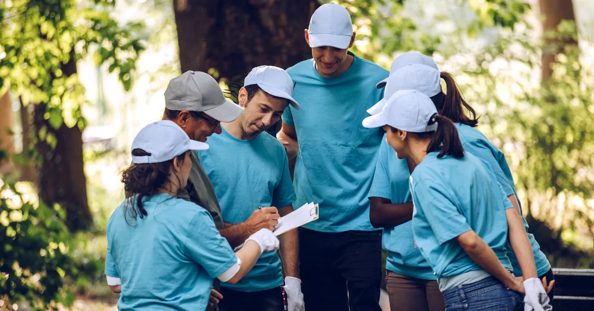 group of people in blue shirts and white hats discussing volunteer plan