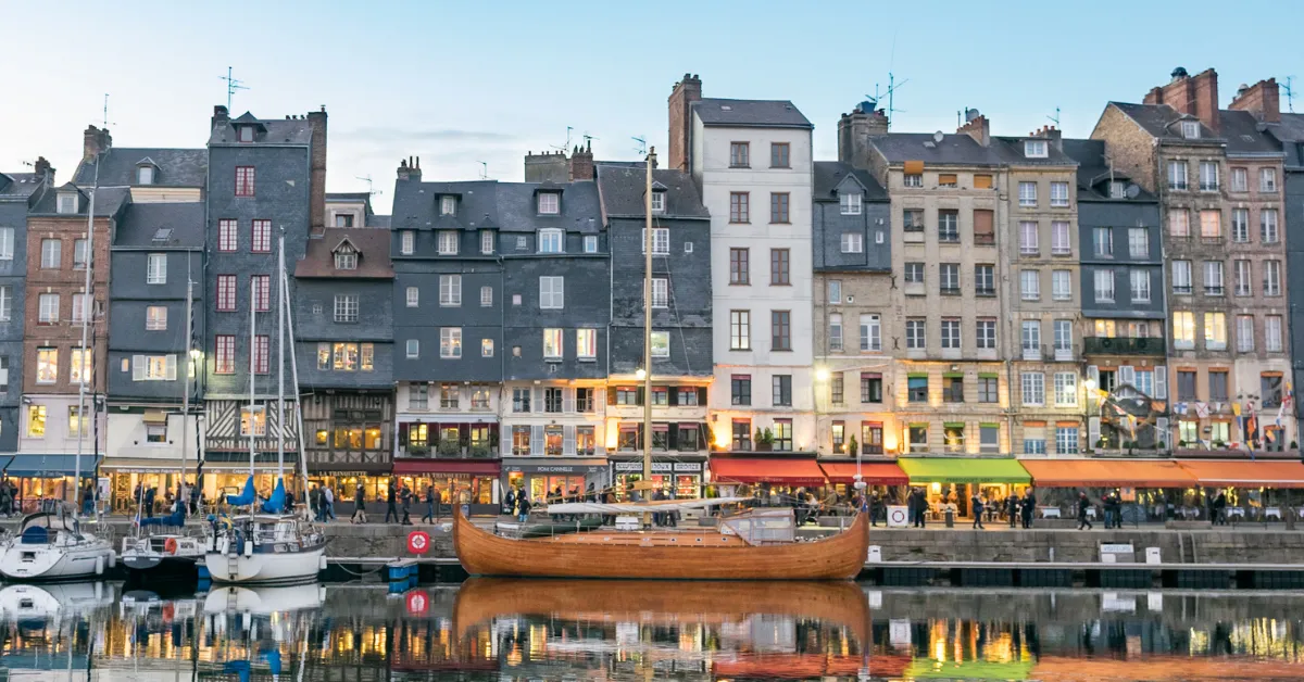 Honfleur city lit up at dusk with docked boats