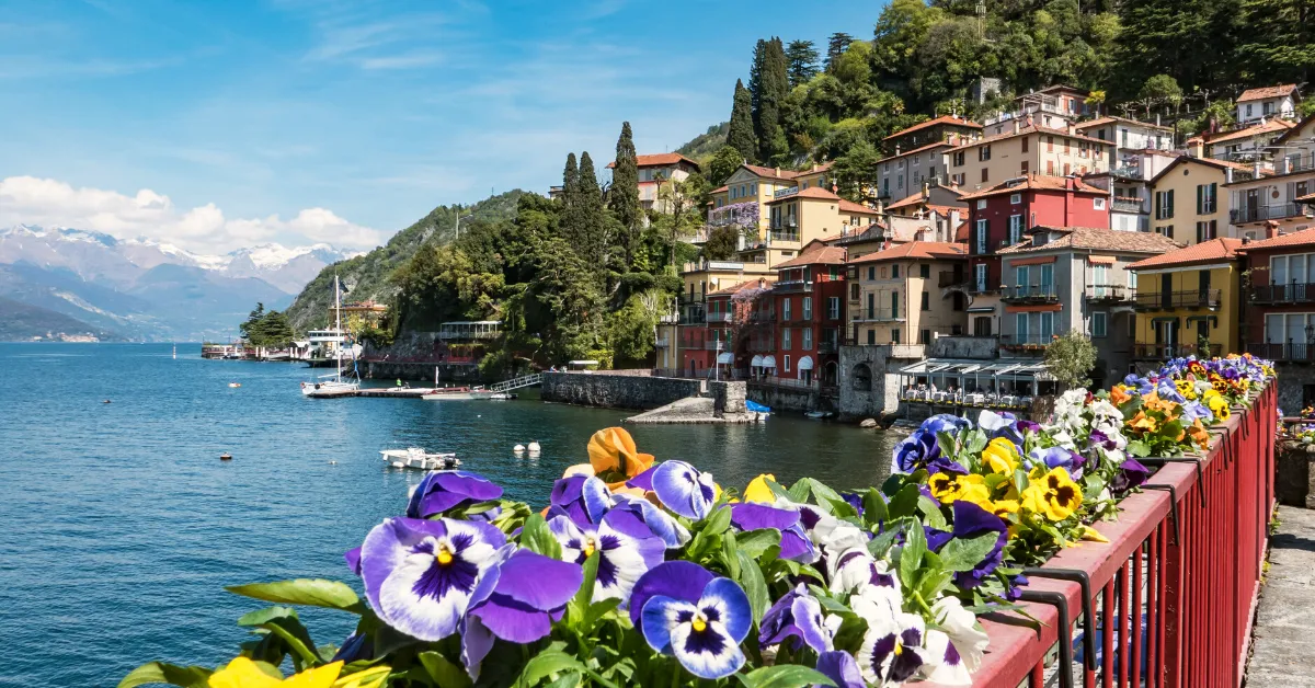 Lake Como with railing lined with colorful flowers