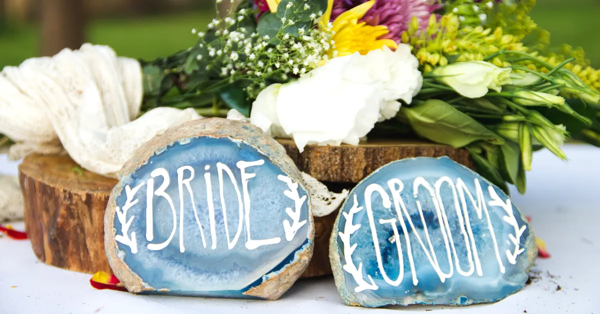 wedding centerpeice of tree stumps with bride and groom written on the front with wildflowers