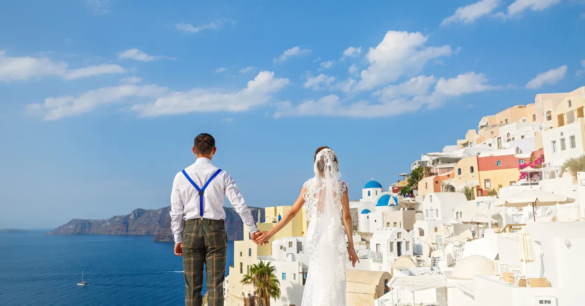couple holding hands look off at the sea and coast of Greece