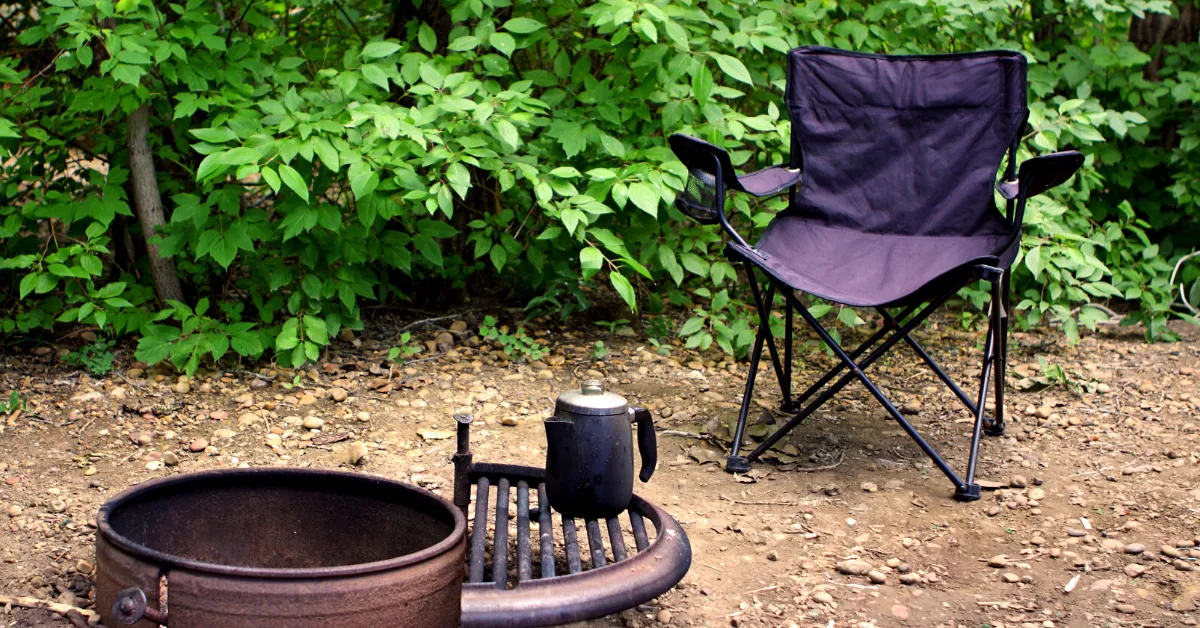 extra large camping chair next to a fire pit and green trees
