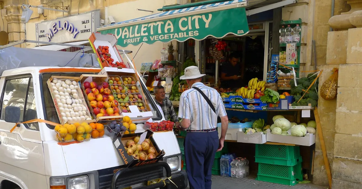 old man standing by fruit stand in malta