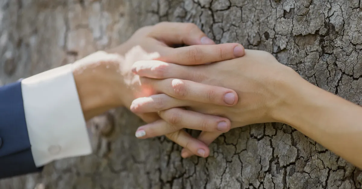 bride and groom holding hands around tree