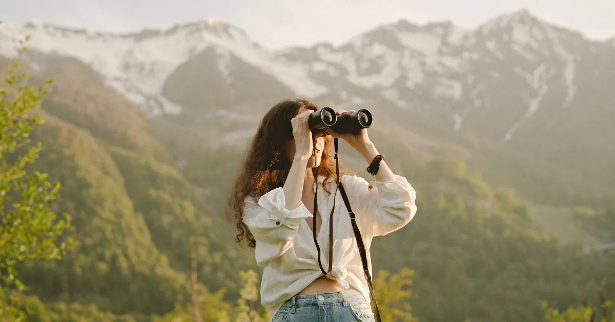 girl using lightweight binoculars for hiking in the mountains