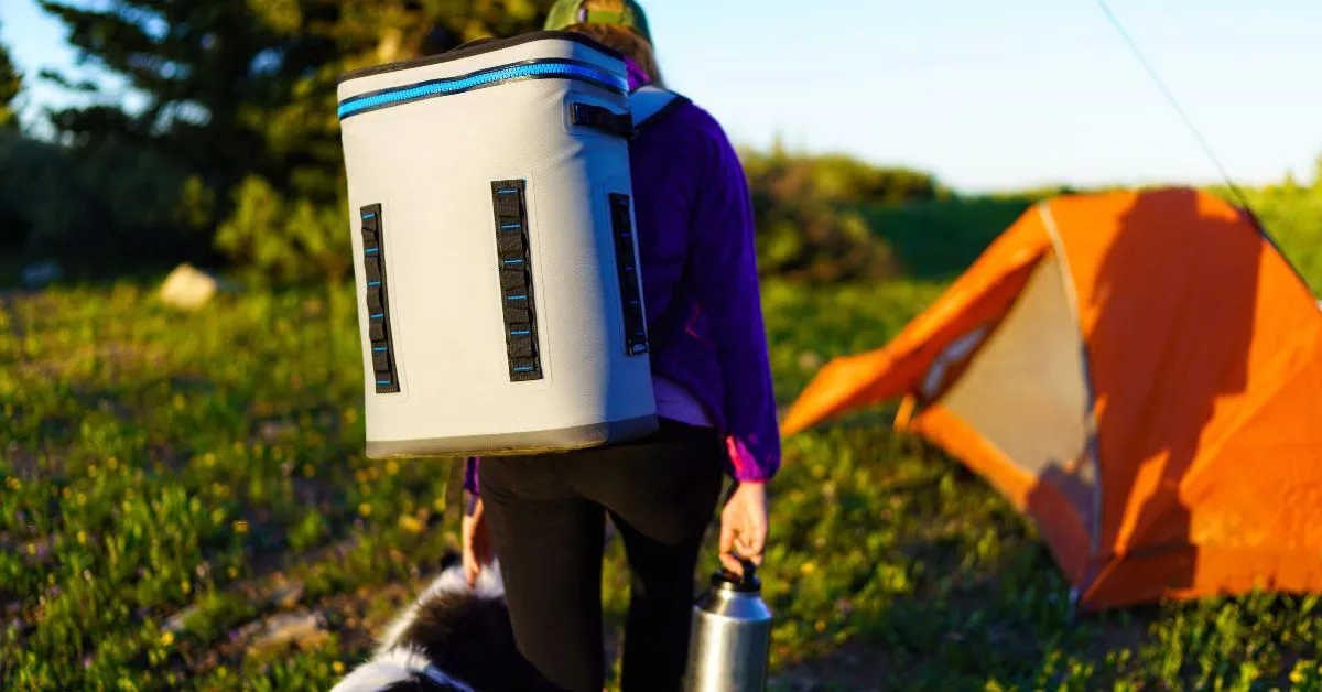 woman carrying a cooler and a thermos while camping