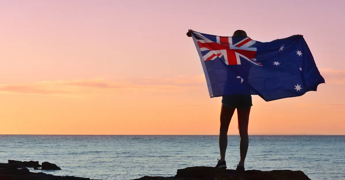A person standing behind an Australian flag at sunset