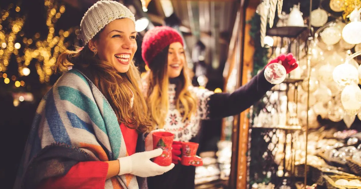 two girls holding mugs at christmas market